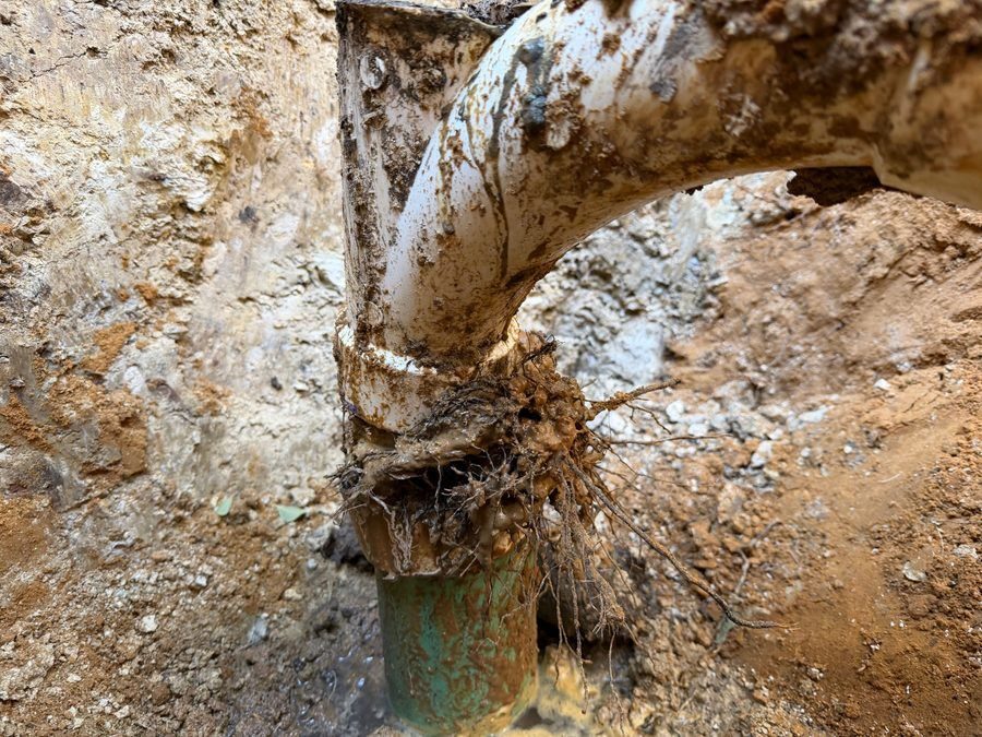 plumber's hand in a glove with a wrench repairing a leaking PVC pipe